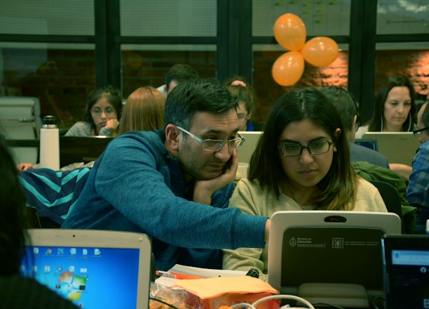 A team collaborating over laptops with code and AI diagrams on screen.