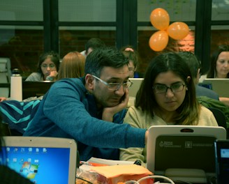A team collaborating over laptops with code and AI diagrams on screen.
