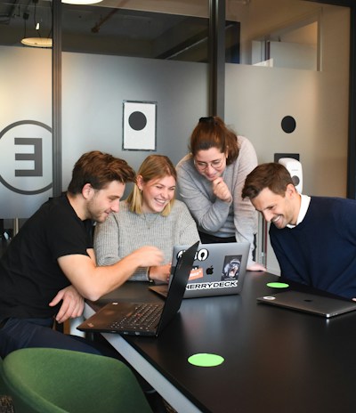 A diverse team of developers collaborating around a laptop displaying cloud-based software architecture.