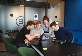 A diverse team of developers collaborating around a laptop displaying cloud-based software architecture.