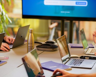 A team collaborating over laptops with code and AI diagrams on screens.